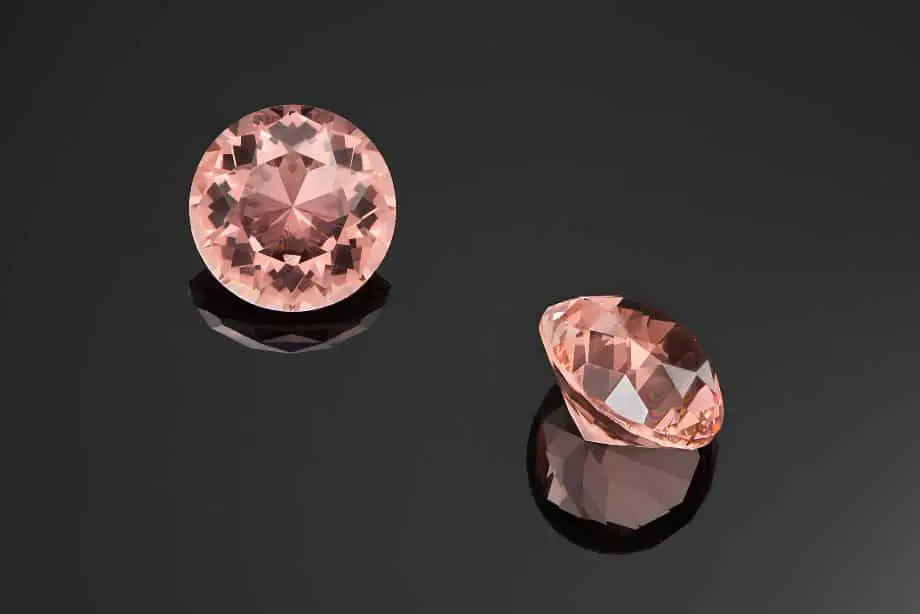 Two pink Morganite round cut gems against a black background